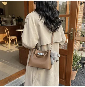 Brown leather bucket bag with silver lock and plush rabbit charm in street scene