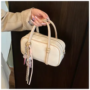 Vue détaillée du sac Boston crème avec des perles rondes et un pendentif à franges