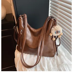 Detail of vintage brown tote bag with decorative zippers and plush pendant accessory