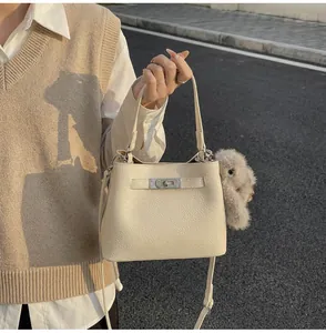 Detail of off-white lychee grain bucket bag with silver hardware and plush bunny charm