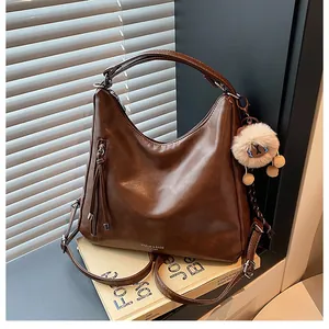 Brown faux leather hobo tote detail showing fringe zipper and plush lion charm