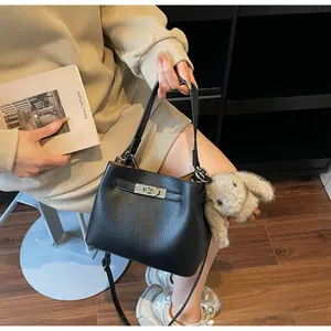Detail of black pebbled leather bucket bag with silver turn-lock and plush bunny charm