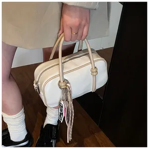 Détail du sac Boston crème avec breloques Long Life et texture en cuir lisse