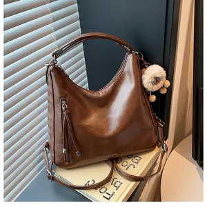 Detail of dark brown leather tote with vertical zipper pocket and tassel charm decoration