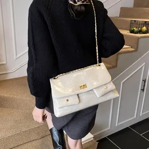 Beige quilted tote bag with gold chain strap and glossy finish shown on model