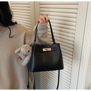 Close-up of black leather bucket bag with pebble texture and cute bunny keychain