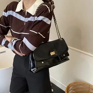 Quilted black leather tote bag with gold chain strap and front pocket detail