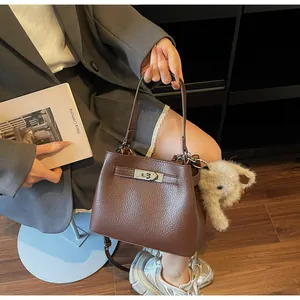 Detail of brown litchi grain leather bucket bag with silver buckle and elephant charm