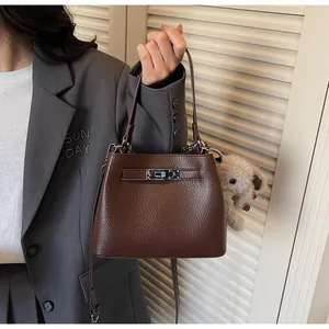 Detail of dark brown lychee grain leather bucket bag with silver lock and plush charm