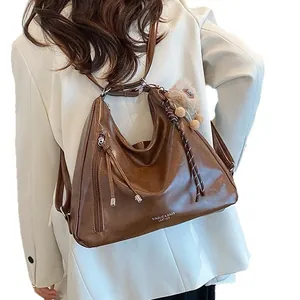 Brown vintage faux leather crossbody hobo bag with braided details and plush charm