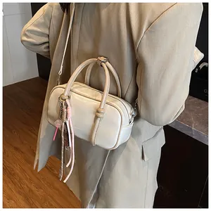 Détail d'un sac à main Boston beige avec texture cuir lisse et pendentif décoratif