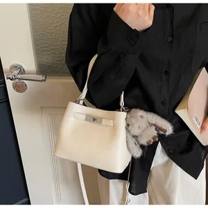 Close-up of a cream white bucket bag in lychee leather with a cute grey bunny charm