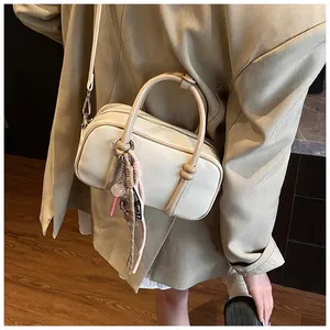Détail du sac Boston crème avec poignées kaki et pendentif sucette rose mignon