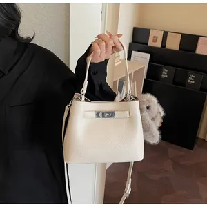 Detail of cream lychee leather bucket bag with silver twist lock and cute bunny pendant