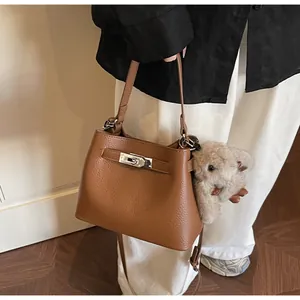 Detail of caramel litchi grain leather bucket bag featuring a silver metal turn-lock