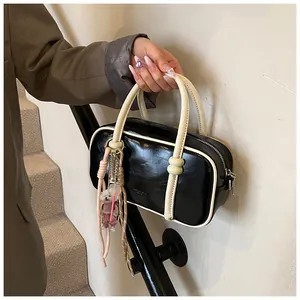 Détail d'un sac Boston noir et blanc avec poignées en perles et charme de chien mignon