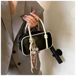 Détail du sac Boston noir avec liseré blanc et breloque chien porté par un mannequin