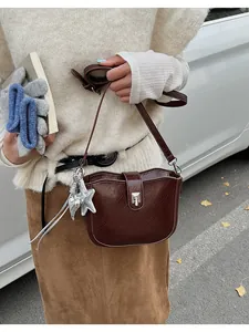 Dettaglio della borsa a tracolla in pelle marrone scuro con ciondolo a stella e fibbia in metallo