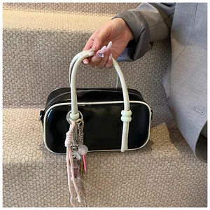 Détail du sac Boston bicolore en cuir noir et blanc avec breloques décoratives colorées