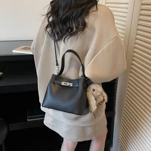 Minimalist black pebble leather bucket bag with silver lock and plush bunny charm