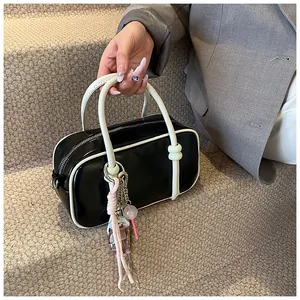Détail du sac Boston noir avec passepoil blanc contrastant et charms décoratifs chic