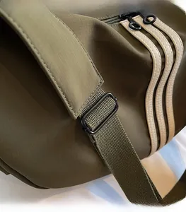 Détail de la bandoulière réglable et de la texture en nylon du sac vert olive