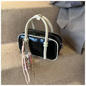 Détail du sac Boston en cuir noir et crème avec des pendentifs décoratifs en peluche