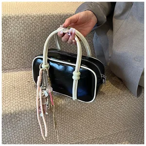 Détail du sac Boston contrasté avec pendentif chien en peluche et chaîne en métal argenté