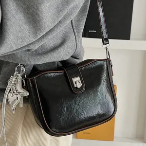 Borsa a spalla minimalista in pelle nera a pieghe con dettagli metallici argentati