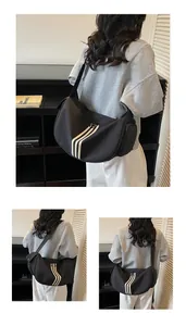 Détail d'un grand sac bandoulière en nylon noir avec trois bandes décoratives blanches