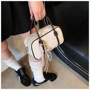 Détail du sac Boston crème avec poignées marron contrastées et fermeture éclair argentée