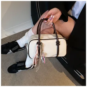 Détail du sac Boston crème avec des bords marron foncé et des pendentifs décoratifs