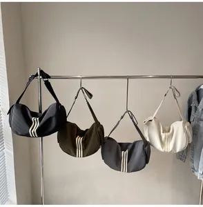 Détail de sacs bandoulière en nylon de plusieurs couleurs avec trois bandes blanches