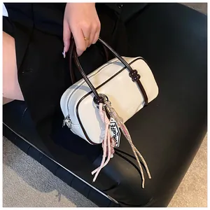 Détail du sac Boston avec pompons roses et garnitures argentées sur cuir noir