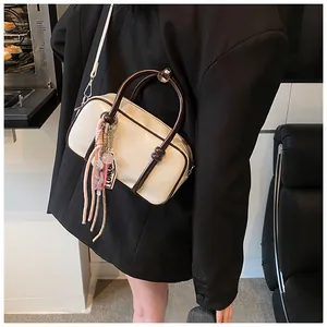 Détail du sac Boston en cuir crème avec bordures marron foncé et pendentif à franges