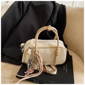 Détail du sac Boston beige avec breloque décorative sur fond de studio sombre élégant