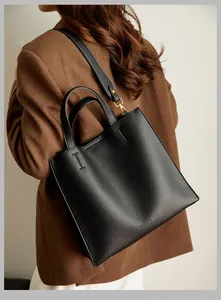 Detail of black lychee grain leather tote bag with gold hardware and shoulder strap