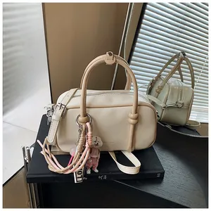 Détail du sac Boston avec doubles poignées, bandoulière réglable et breloque chiot