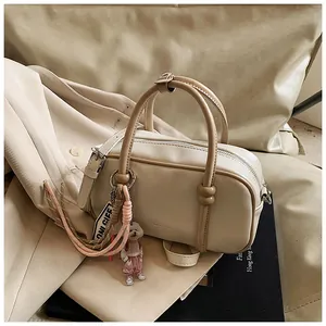 Détail du sac Boston crème avec poignées kaki contrastées et accessoire pendentif chien