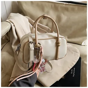 Détail d'un sac Boston beige avec poignées marron et charms décoratifs mignons