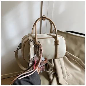 Détail d'un sac Boston crème avec poignées kaki et breloques décoratives mignonnes