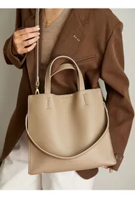 Macro detail of lychee texture leather and logo debossing on a khaki tote bag