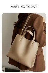 Detail of taupe lychee texture tote bag with gold hardware and logo on a chic wool blazer