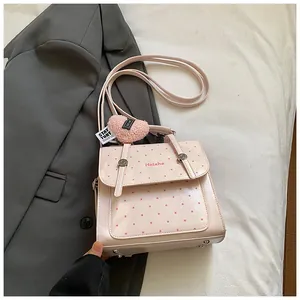 Detail der rosa gepunkteten Handtasche mit Herz-Plüschanhänger und verstellbarem Gurt