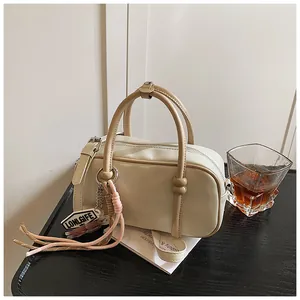 Détail du sac Boston avec doubles poignées en cuir et fermeture éclair dorée