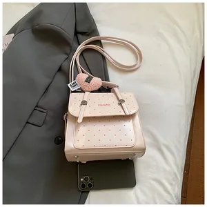 Detailansicht eines rosa gepunkteten Minirucksacks mit Herzanhänger und Handy zum Vergleich