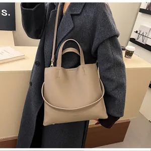 Detail of khaki lychee grain leather tote bag with dual handles and long shoulder strap