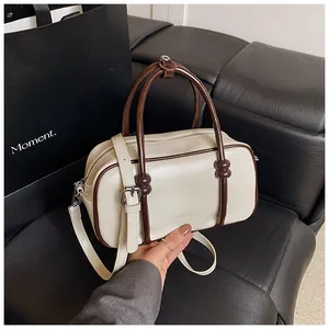 Détail du sac Boston montrant le cuir crème et les accents marrons sur la poignée