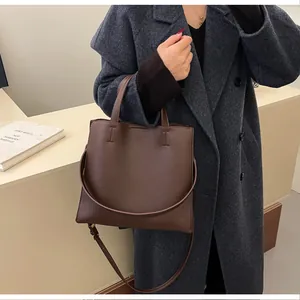 Close-up of brown lychee grain leather tote bag with sturdy handles and shoulder strap