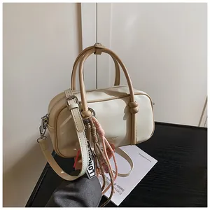 Gros plan détaillé du sac Boston crème avec texture cuir et breloque tissée